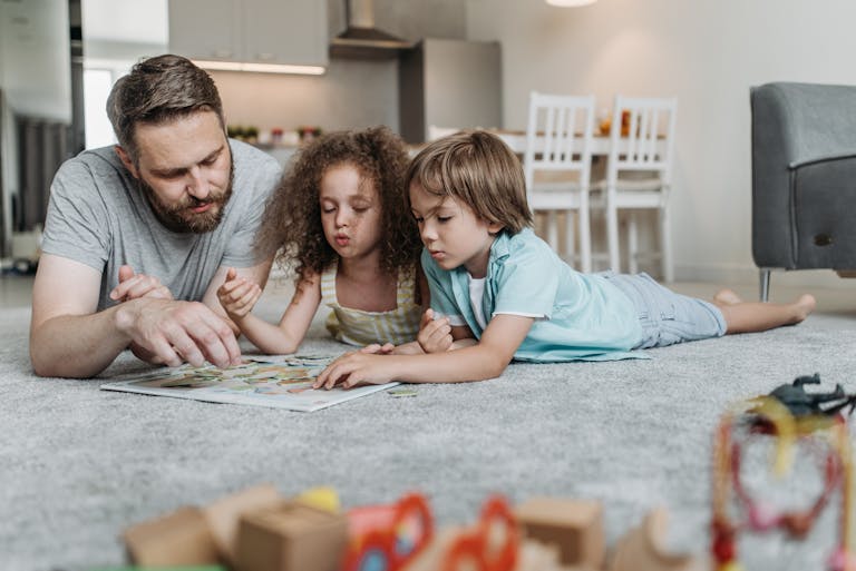 A father and his children enjoying quality time solving a puzzle on the living room floor.